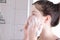 Young girl soap her face with soap in the bathroom