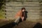 Young girl squats on the floor in front of a cabin, looks down