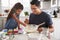 Young girl standing at the kitchen table preparing a cake mix with her father, close up