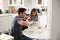 Young girl standing at the kitchen table preparing cake mixture with her father, seen from doorway