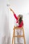 Young girl standing on a ladder painting the walls