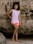 Young girl standing near the rock. Happy childhood. Spending time on the beach. Girl wearing shorts. Vacation in Asia. Pandawa