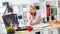 A young girl is standing near a table, talking on the phone and holding a marker in her hand. On the table is a magnetic