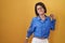 Young girl standing over yellow background stretching back, tired and relaxed, sleepy and yawning for early morning