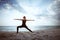 Young girl standing in yoga warrior asana on dreamlike beach on summer vacation