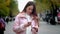 A young girl stands on a city street. Holding a smartphone and a bank card. Makes electronic payment by credit card via