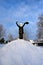 young girl stands on large pile of snow and holds shovel over her head. Teenage girl helps adults clean up snow