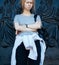 A young girl stands leaning on the door of the church. Skeptical look.