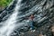 Young girl stands near waterfall and holds out arms to it