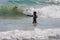 Young Girl Stands In Shallow Ocean Water Surrounded By Waves Filled With Sea Weed and Sea Kelp She is Watching As A Wave Breaks C