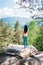 Young girl staying on the rock and looking on mountains landscape