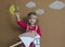 Young girl on stick horse. Handmade. Background of painted sun and white clouds