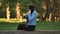 A young girl strokes her long hair while sitting in the park.