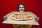 Young girl student with a big tasty pizza in a box on a red background, a hungry girl holds fast food