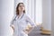 Young girl student at a medical university standing in the corridor, portrait of an attractive nurse near the hospital, happy