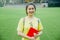 Young girl student portrait smiling with a book on grass field in the afternoon in campus