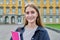 Young girl student posing outdoors, background of educational building