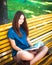 Young girl student sitting on yellow bench