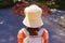 Young girl with a stylish backpack in straw hat in a rose garden