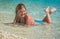 Young girl sunbathing in sea water splashing around her