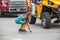 Young girl surrounded by tires of large vehicles grabs candy thrown from floats in small town parade