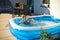 Young girl swimming in inflatable swimming pool on home backyard terrace. Staycation sta home concept