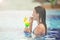 Young girl at swimming pool drinking cocktail