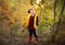Young girl with tail and yellow waistcoat posing in the autumn forest. Copy space