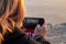 A young  girl takes a photo with her mobile phone of the sunrise on the fortress wall in the ruins of the Masada fortress, in