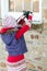 Young girl taking an overhead photograph of icicles hanging from a stone window ledge