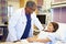 Young Girl Talking To Male Doctor In Hospital Room