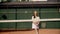 A young girl tennis player trains on the court at medium pace. A lady athlete prepares for international competitions or