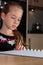 Young girl thinking while doing homework at the kitchen table holding pencil