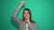 Young girl thinking and having an idea pointing hand up isolated over green background