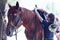 A young girl to saddle a brown horse in the forest. Children`s equestrian camp. Summer sports camp for children. A cute girl is