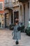 Young girl tourist in a fashionable brown hat is walking down the street with a cobblestone. Vertical photo.