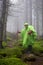 Young girl tourist in a foggy forest in the mountains. Hiker with waterproof gear and backpack in the rain on an adventure. Travel
