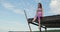 Young girl in tracksuit sits on pier on the seashore, ocean and dangles her legs. Woman sitting on the pier on the berg