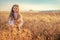 Young girl with traditional Bulgarian folklore costume at the agricultural wheat field during harvest time with industrial combine