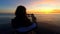 A young girl traveler photogfies a colorful sea sunset on a mobile phone