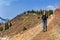 Young girl with trekking sticks walks along the mountain trail