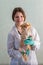 A young girl veterinarian is holding a redheaded chihuahua and smiling