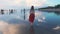 Young girl walking on the beach with reflections