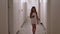 Young girl walking on hotel corridor with mobile phone. Teenager girl using smartphone in long hotel hall. Tourist girl