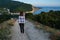 Young girl walking on a mountain road with town view wrapped in a blanket. Cool summer evening. Back