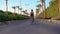 Young girl walking on the road with palm trees
