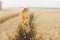 A young girl walks along a path in a field sown with barley