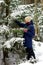 A young girl walks through a snowy coniferous forest and enjoys nature