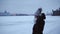 Young girl in a warm jacket and hat in the cold. Young woman on a background of snowdrifts and a snowy city. Winter