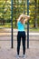 Young girl warms up and stretches on sports ground in the park